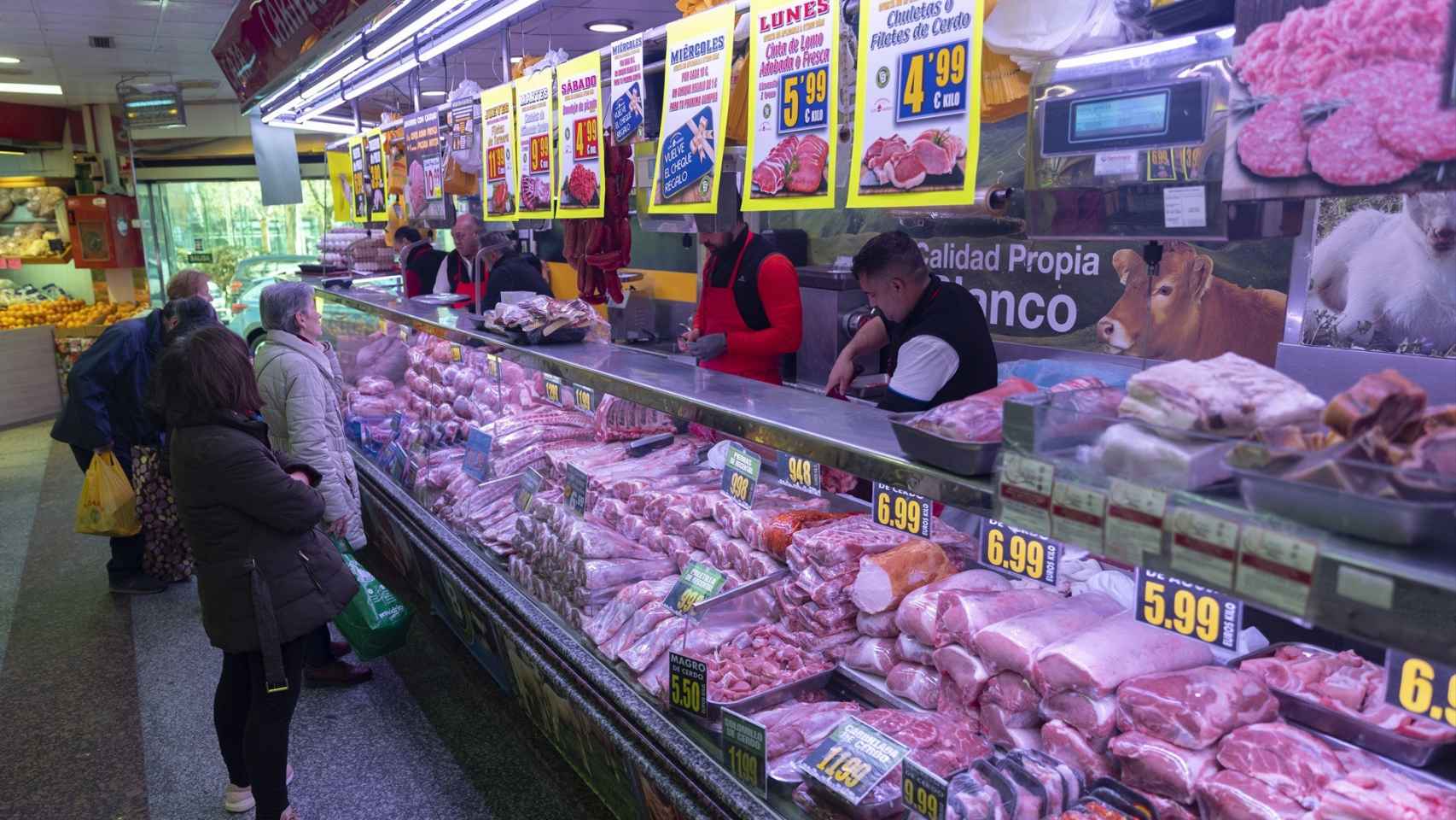 Varias personas compran en una carnicería en un mercado