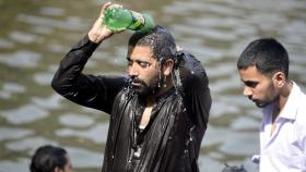Imagen de archivo de un hombre refrescándose con una botella de agua en plena ola de calor.