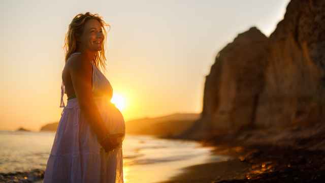 Una mujer feliz embarazada disfrutando en la playa del atardecer.