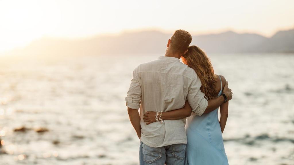 Pareja despidiéndose frente a una puesta de sol.