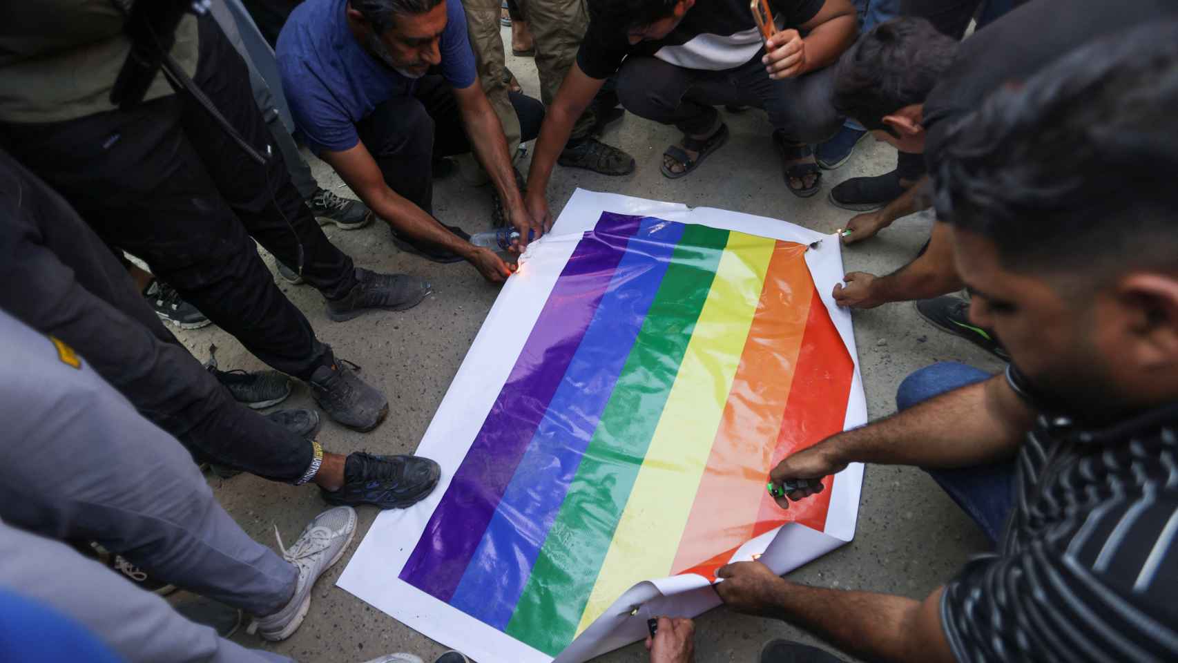 Los manifestantes tratan de quemar una pancarta con la bandera LGBTQ cerca de la embajada sueca en Bagdad.