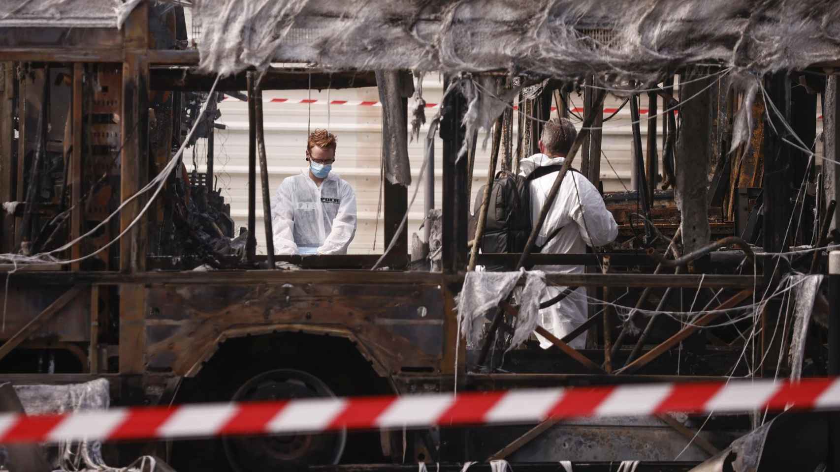 La Policía Científica de Francia examina los restos de un bus quemado la noche de ayer por las protestas