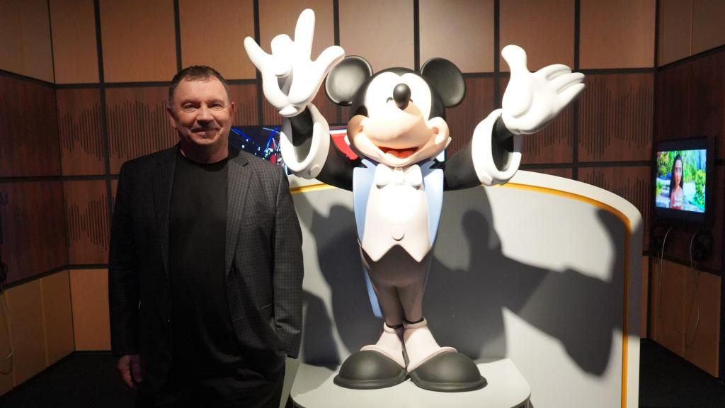 El animador Andreas Deja posando junto a la escultura de Mickey en Disney100: The exhibition en Múnich.