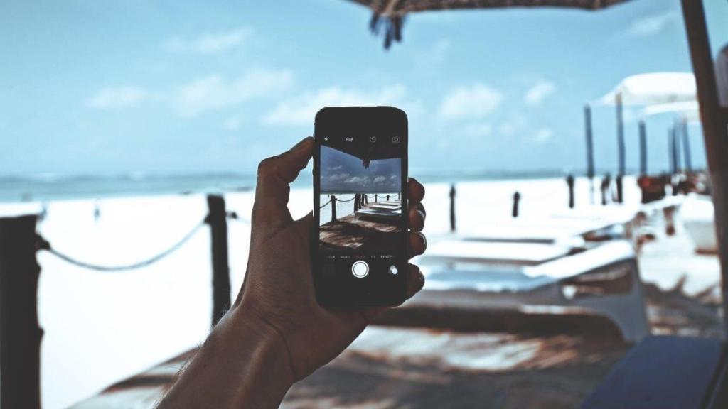 Una persona utiliza un teléfono móvil en la playa.