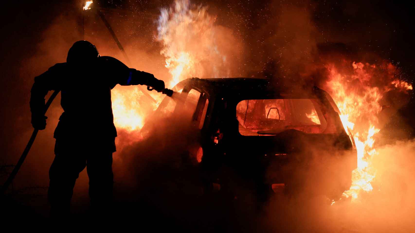 Un bombero francés trabaja por extinguir el fuego del coche en el quinto día de protestas en Francia.