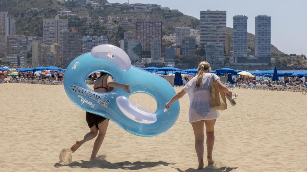 Dos turistas en una playa de Benidorm, con el 'skyline' de fondo, este fin de semana.