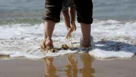 Dos personas mojándose los pies en la orilla de una playa