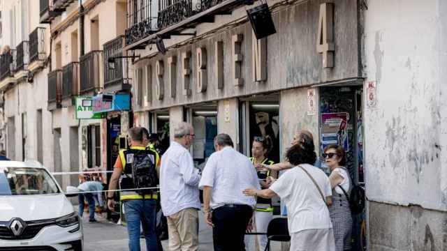 Policías atienden a un familiar de la mujer apuñalada en la tienda de ropa de trabajo ‘Vistebien’, en la plaza de Tirso de Molina.