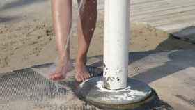 Una persona quitándose la arena en un sistema de lavapiés de una playa.