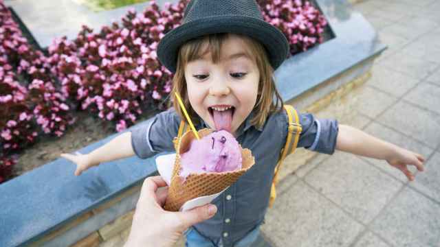 Una niña probando un helado de fresa.