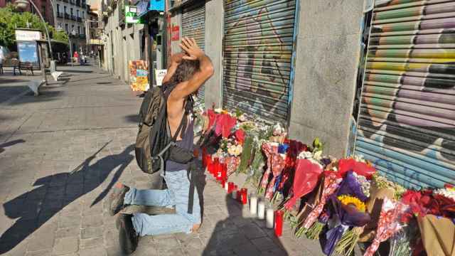 Un hombre se arrodilla ante la ofrenda floral que rinde homenaje a Concha, asesinada en Tirso de Molina.