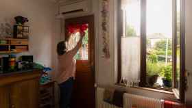 Una mujer baja las persianas y estores de su vivienda.