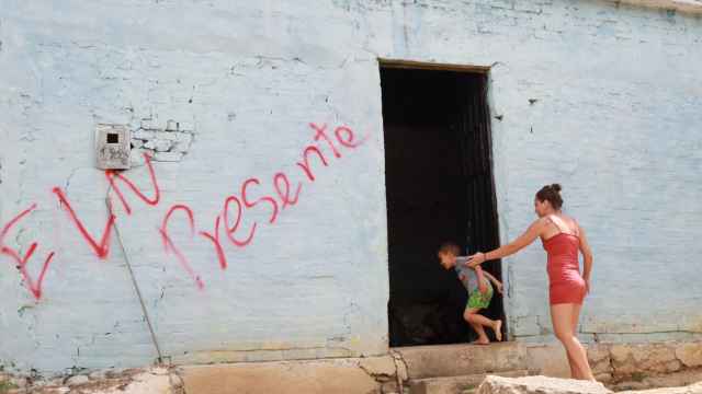 Una mujer y un niño entran a una casa marcada con un grafiti del ELN, el miércoles en Cúcuta.