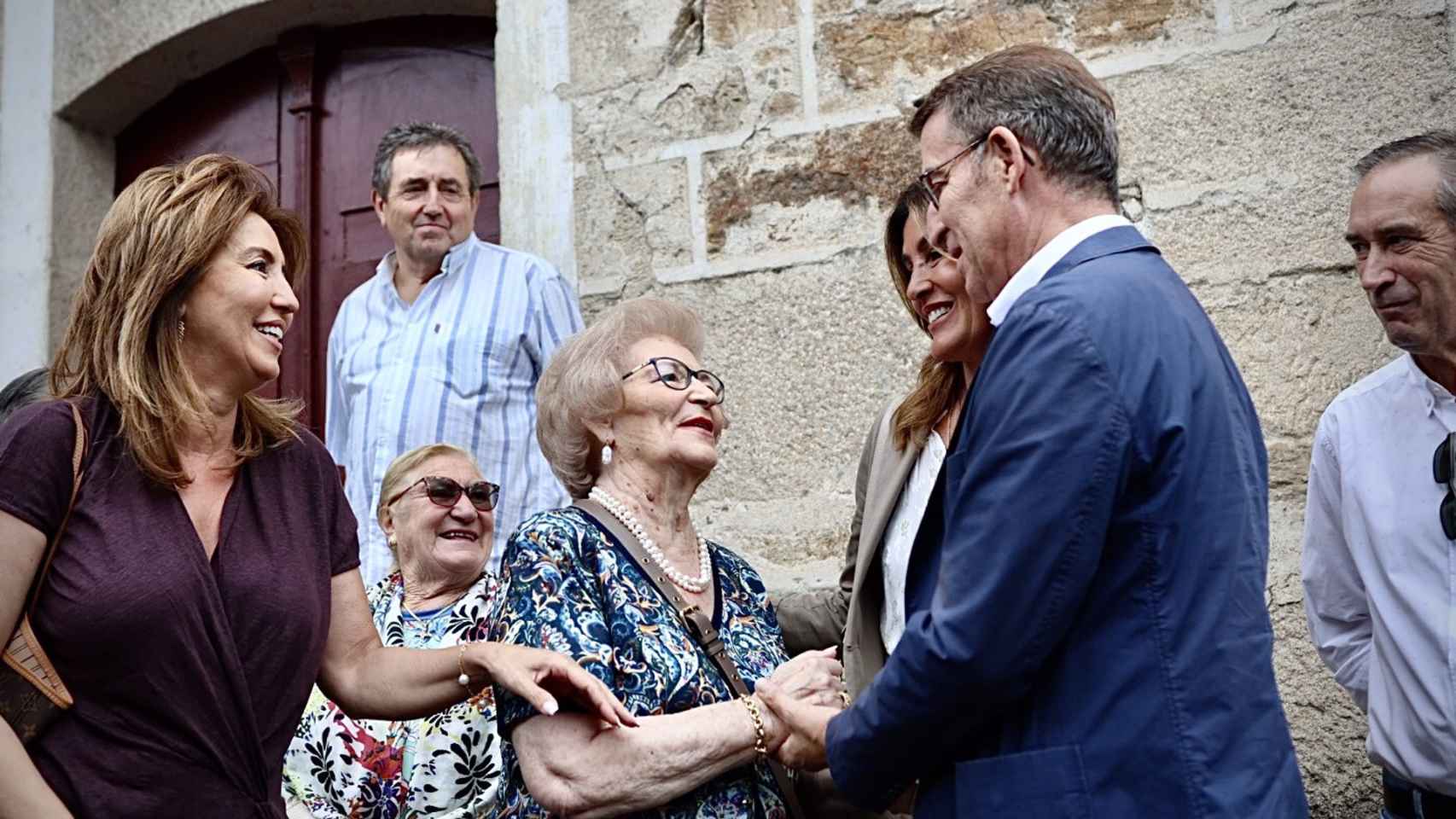 El líder del Partido Popular, Alberto Núñez Feijóo, saluda a su madre a su llegada a la plaza mayor de Os Peares.