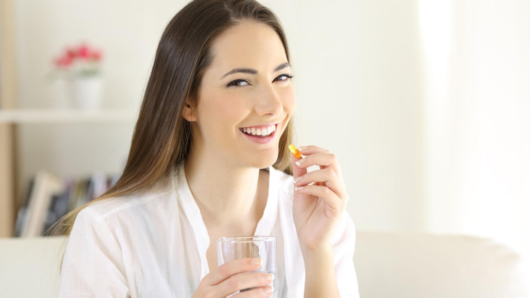 Una mujer tomando un suplemento nutricional.