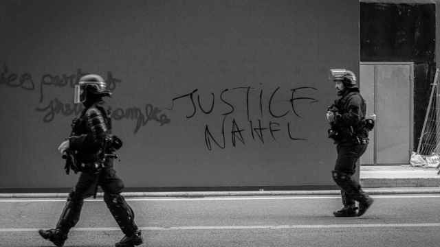 Policías antidisturbios frente a una pintada pidiendo Justicia para Nahel en París.