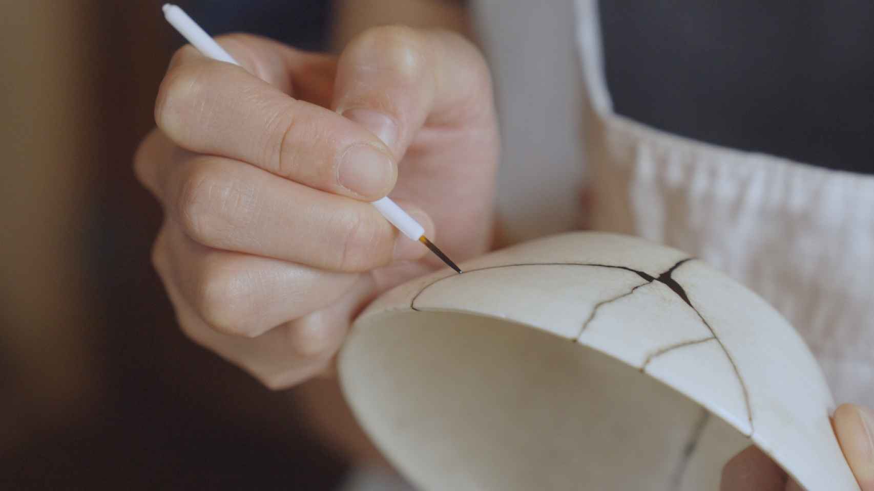 Una mujer repara las grietas de un cuenco de cerámica.
