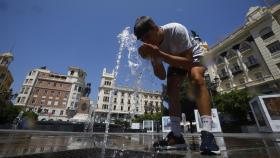 Un joven se refresca en una de las fuentes del centro de Córdoba.