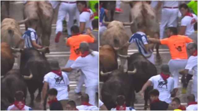 Un participante empuja a otro contra los toros durante el tercer encierro de las fiestas de San Fermín 2023.