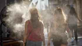 Varias personas caminan al lado de un difusor de vapor de agua.