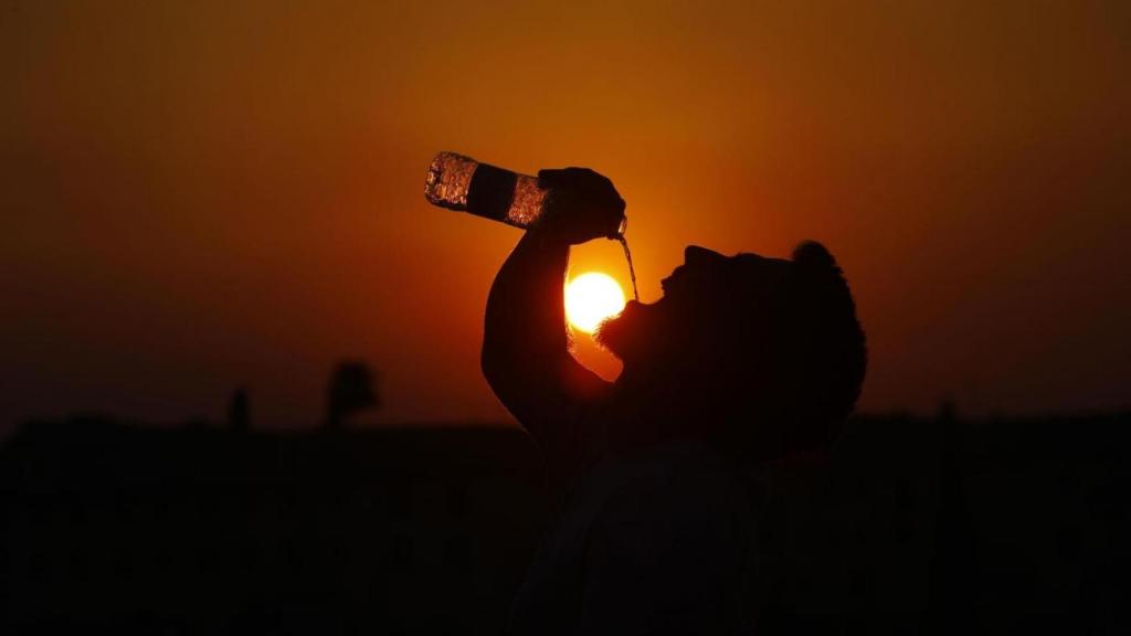 Un hombre bebe agua en el puente romano de Córdoba donde las temperaturas han alcanzado los 43º.