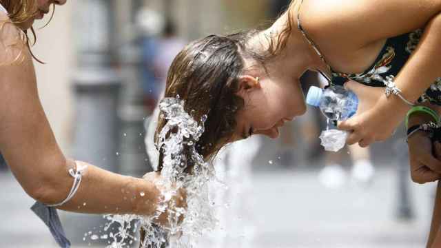 Una persona se refresca en una fuente durante una ola de calor, en imagen de archivo.