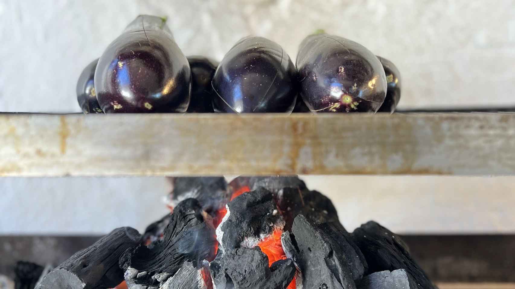 Cocinando berenjenas a la parrilla directamente sobre el fuego del carbón