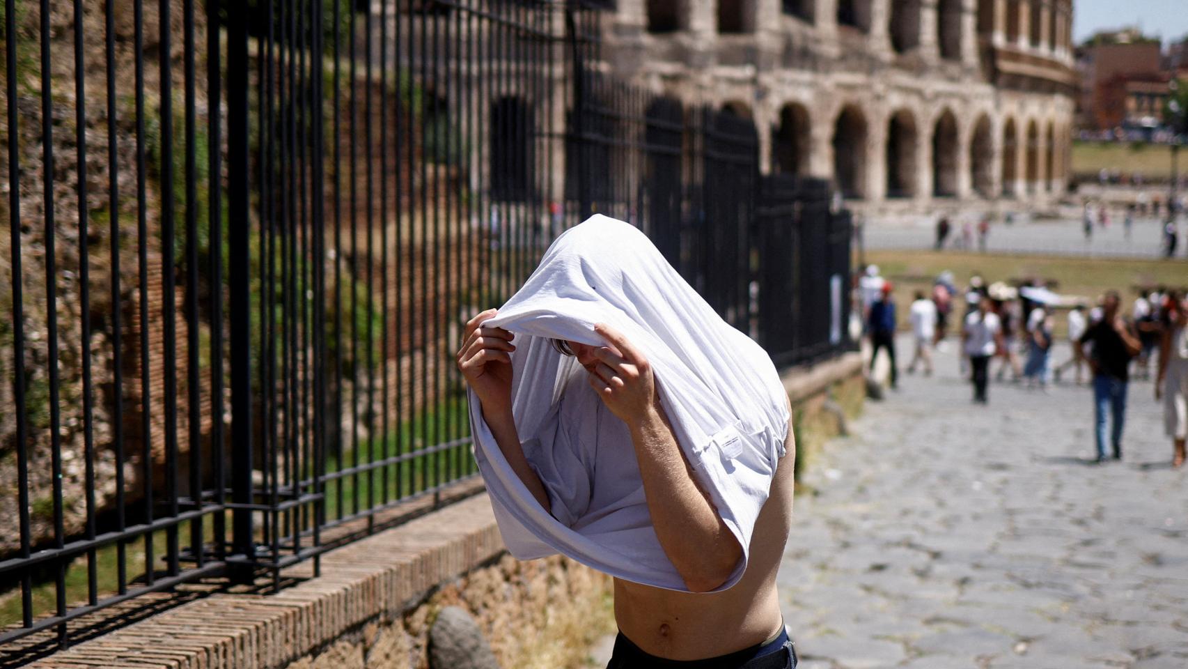 Un turista busca abrigo contra el sol junto al Coliseo.