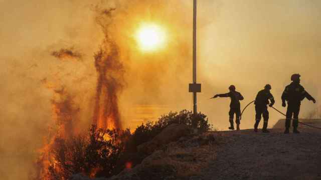 Bomberos griegos luchan contra las llamas en Saronida, cerca de Atenas.