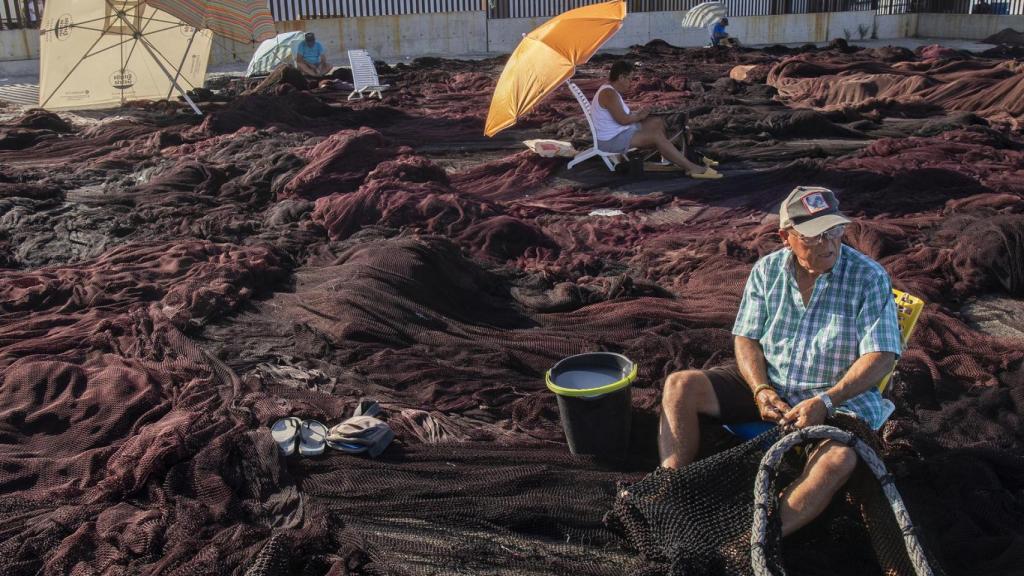 Unos pescadores arreglan artes de pesca en el muelle de Barbate (Cádiz).