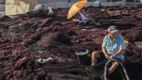 Unos pescadores arreglan artes de pesca en el muelle de Barbate (Cádiz).