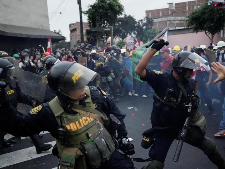 Policías antidisturbios cargan contra manifestantes antigubernamentales, en Lima (Perú).