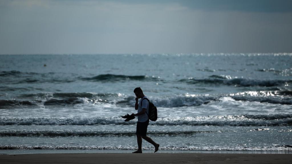 Una persona descansa frente a una playa valenciana, en imagen de archivo.