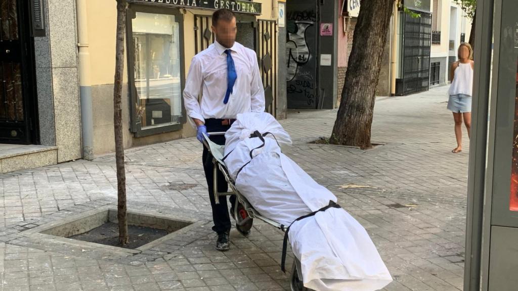 Empleado de una funeraria transportando el cuerpo sin vida de Antonio, fallecido este viernes en un incendio en Chamberí.