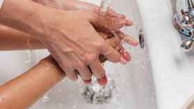 Dos personas se lavan las manos con agua.