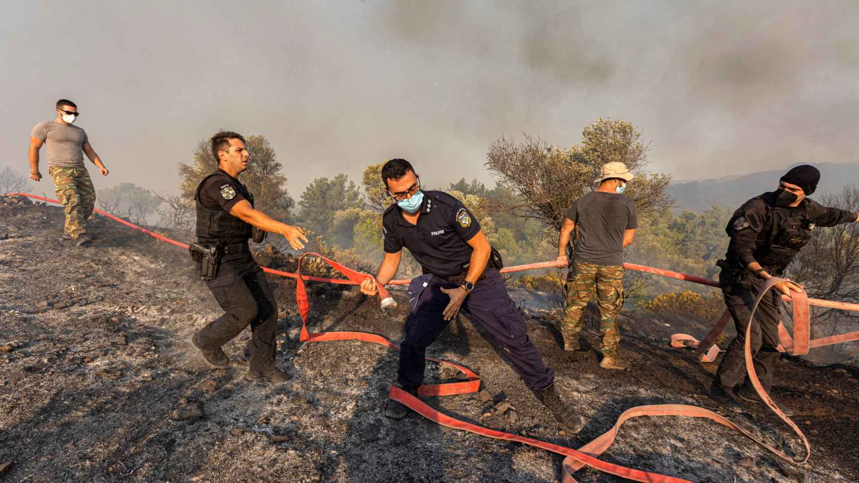 Bomberos, voluntarios y policías operan mientras un incendio forestal arde cerca del pueblo de Asklipieio, en la isla de Rodas, Grecia. ,