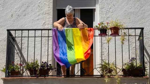 Una mujer cuelga una bandera LGTBI en su casa de Náquera (Valencia).
