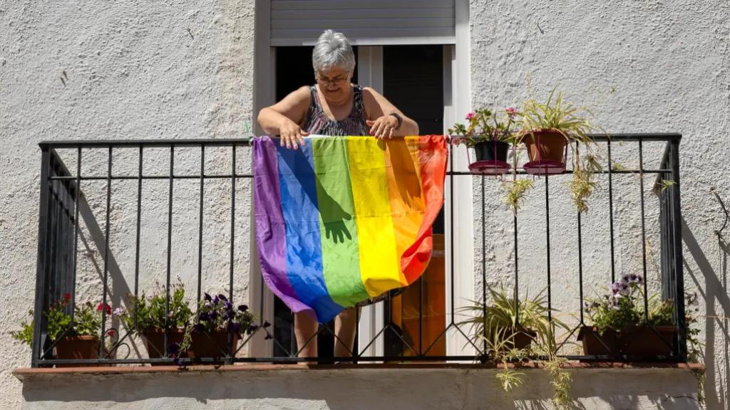 Una mujer cuelga una bandera LGTBI en su casa de Náquera (Valencia).