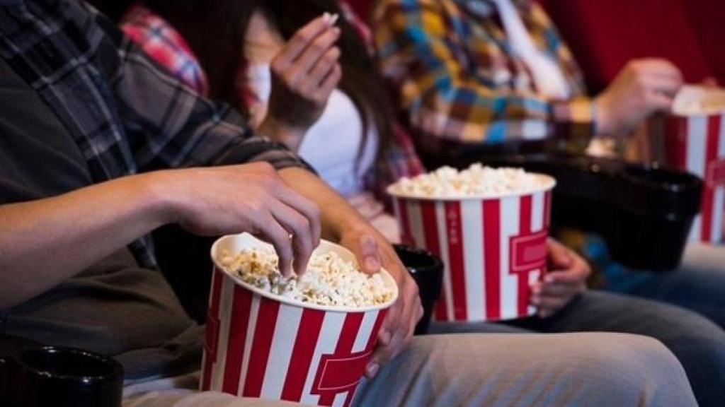 Una persona con palomitas en el interior de una sala de cine.