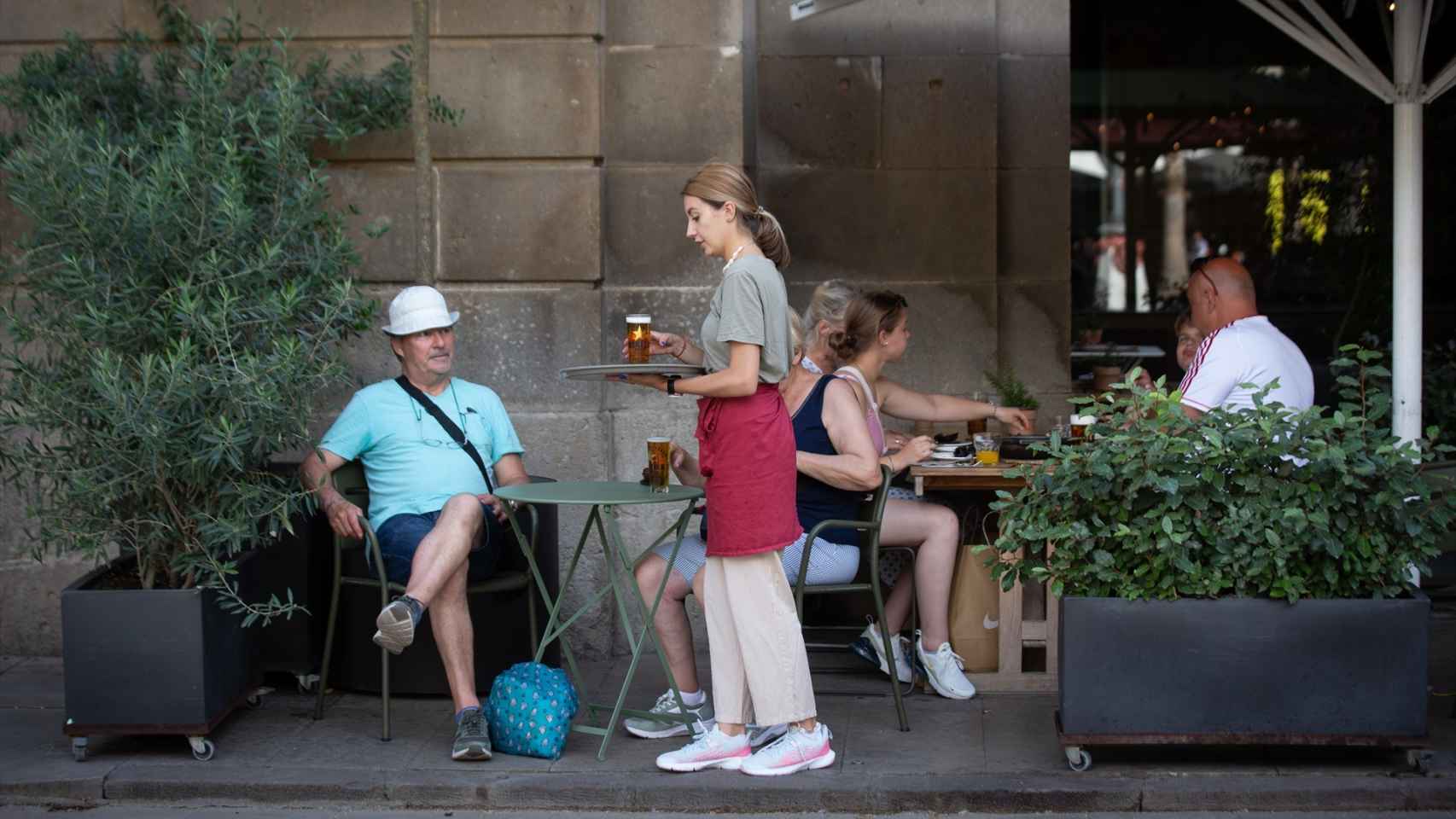 Una camarera sostiene una bandeja en la plaza Real de Barcelona.
