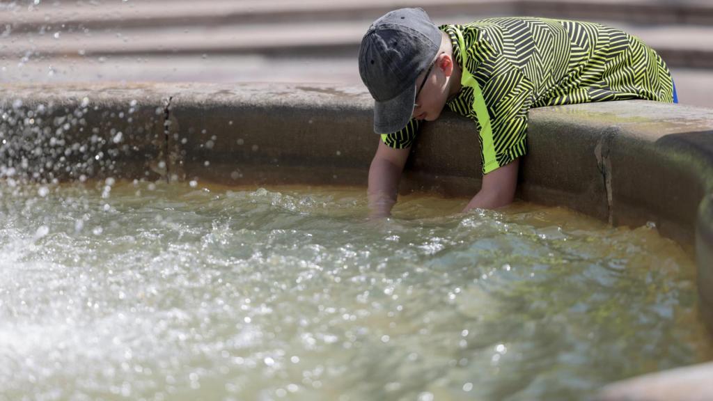 Un niño se refresca por la ola de calor.