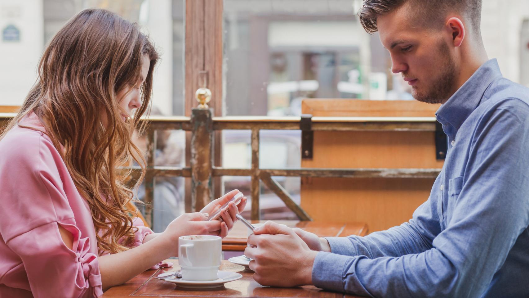 Una pareja se ignora mutuamente mirando el móvil.