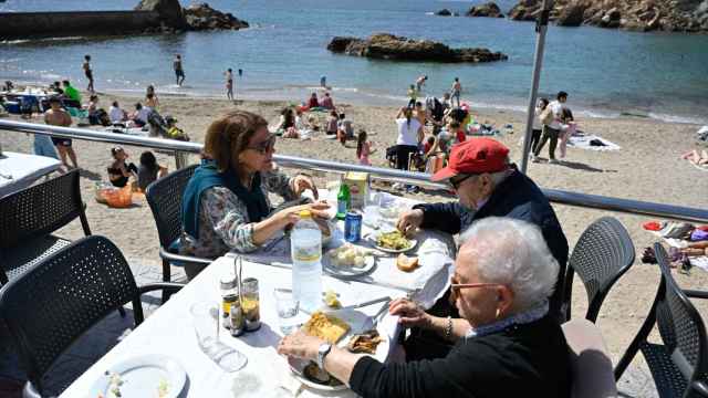 Unas personas comen en una terraza junto al mar.