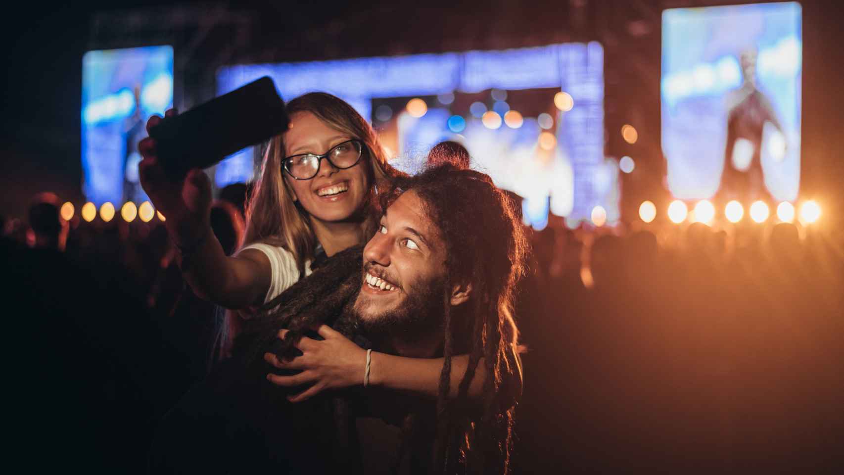 Una pareja haciéndose un selfie de noche en un concierto