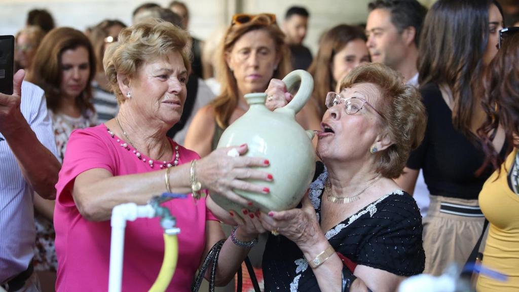 Dos toledanas cumplen con la tradición de beber agua de los botijos en la Catedral.