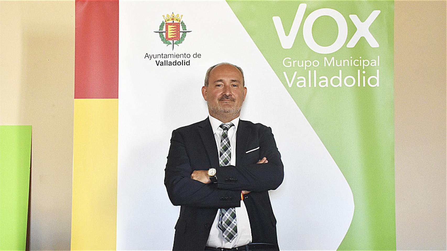 Alberto Cuadrado, concejal de Salud Pública y Seguridad Ciudadana en el Ayuntamiento de Valladolid con el cartel de su grupo de fondo