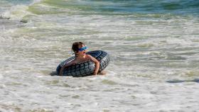 Un niño con un flotador en una playa.
