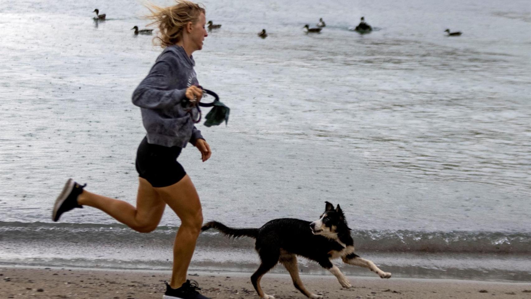 Una mujer con su perro en una playa española.