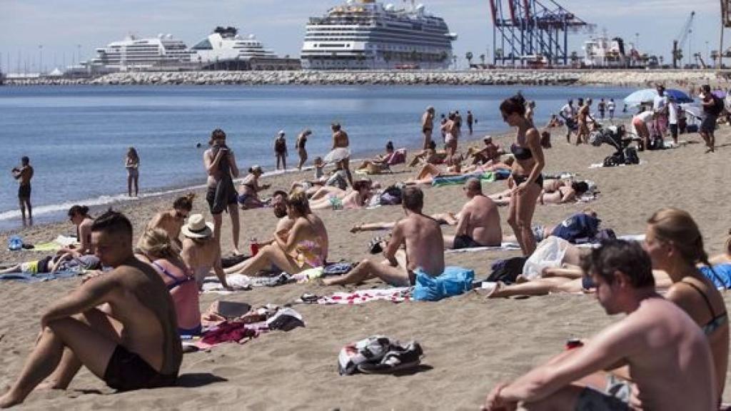 Varias personas tomando el sol en una playa de España.