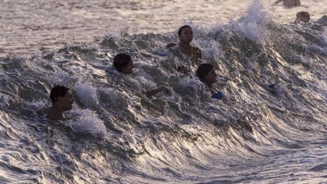 Numerosas personas se bañan este jueves, en la playa de la Malagueta (Málaga) a última hora de la tarde noche.
